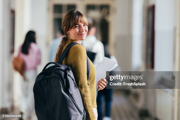 lächelnder college-student, der durch den universitätsflur geht - students stock-fotos und bilder