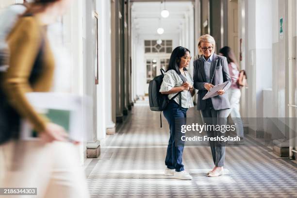 insegnante e studente discutono del lavoro in un corridoio della scuola - corridoio caratteristica di una costruzione foto e immagini stock