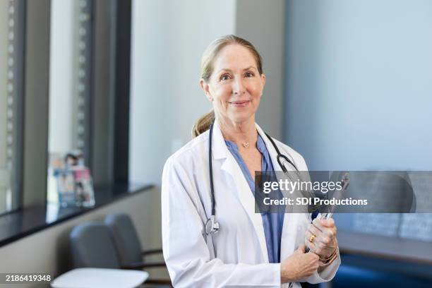 caring female doctor smiles at camera - female doctor stock pictures, royalty-free photos & images