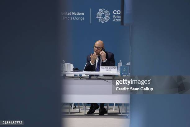 Executive Secretary Simon Stiell talks on a phone as he sits in a meeting room on day twelve at the UNFCCC COP29 Climate Conference on November 23,...