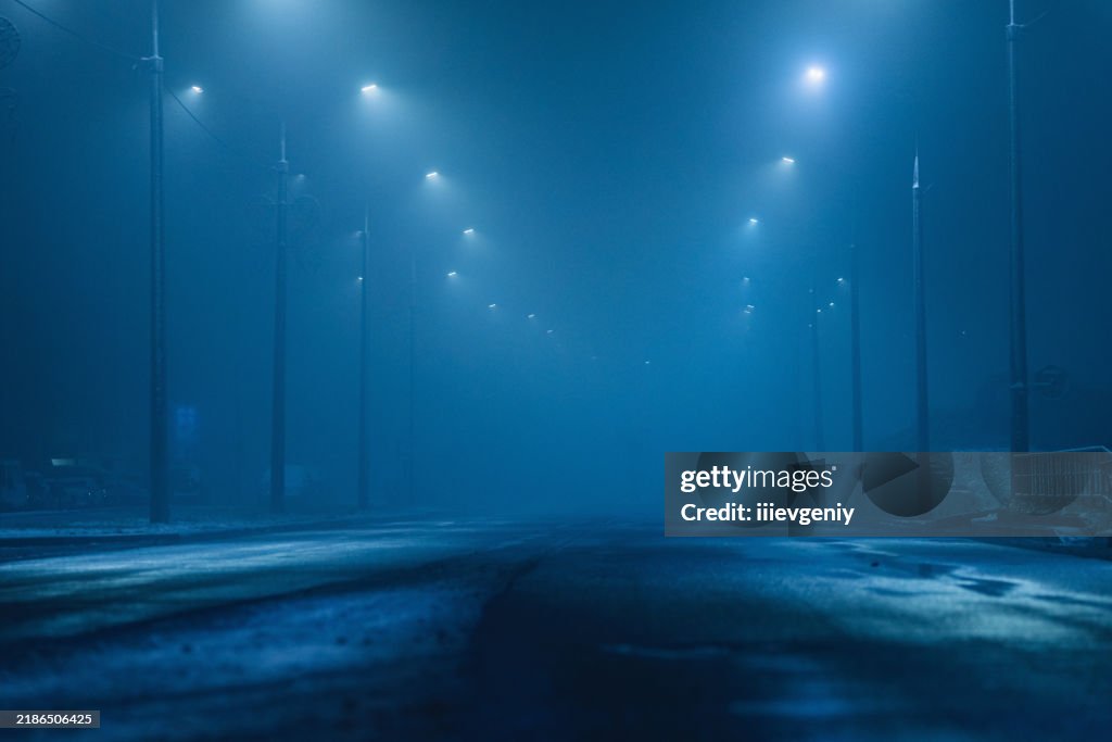 Foggy weather. Lanterns by the road. Night city