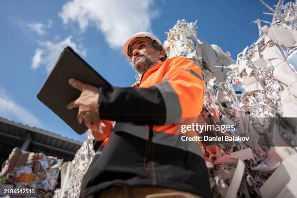 worker inspects compacted waste bales in recycling factory - afvalverwerking stockfoto's en -beelden
