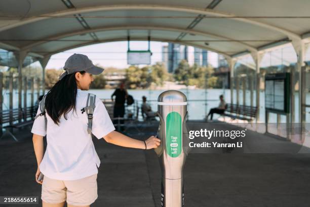 woman tapping her card at a waterfront transportation terminal - tapping stock pictures, royalty-free photos & images