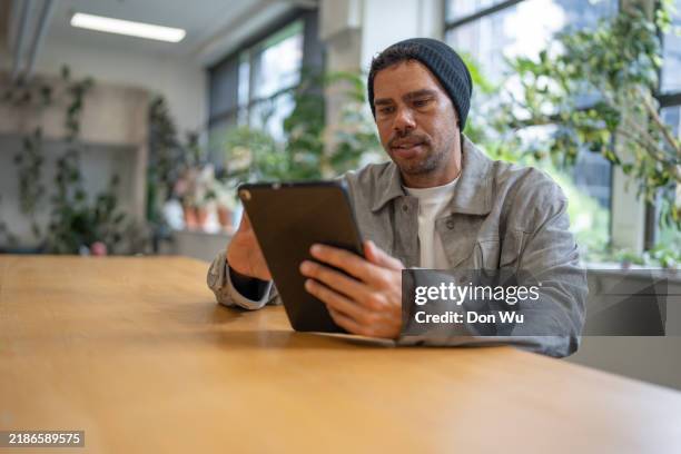 man using a tablet indoors - native man stock pictures, royalty-free photos & images