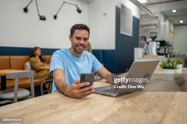 young entrepreneur checking smartphone while working remotely - native man stock pictures, royalty-free photos & images