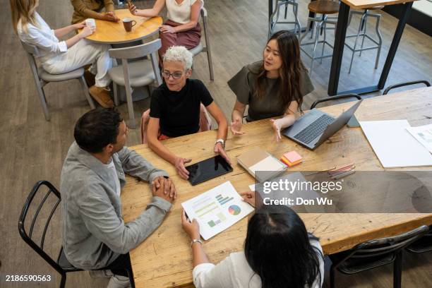 high angle view of a diverse team collaborating over data at a cafe - sri lankan ethnicity stock pictures, royalty-free photos & images