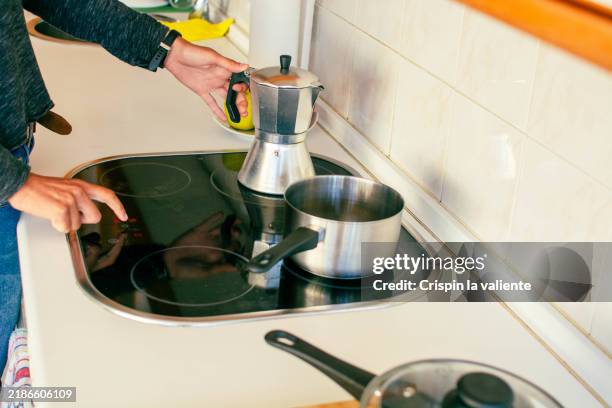 woman turning on the vitroceramic stove to prepare breakfast - placa de fogão vitrocerâmica imagens e fotografias de stock