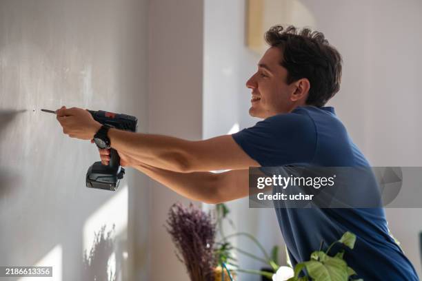 handyman using cordless drill to screw into wall - schroevendraaier stockfoto's en -beelden