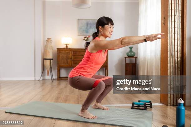 determined woman doing exercise at home with resistance sport band - crouching stock pictures, royalty-free photos & images