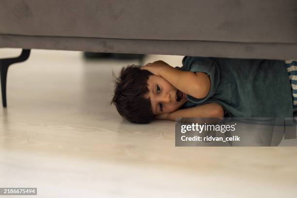 enfant caché sous le canapé - monstre photos et images de collection