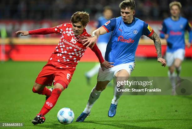 Kaishu Sano of Mainz is challenged by Nicolai Remberg of Kiel during the Bundesliga match between Holstein Kiel and 1. FSV Mainz 05 at...