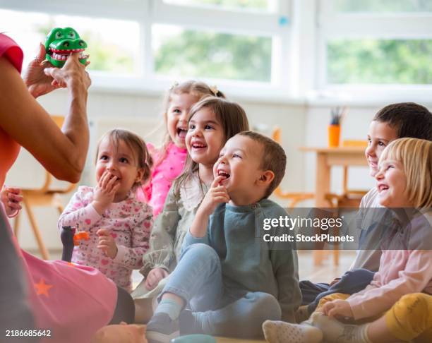 the teacher entertains the children in the kindergarten - peuterschool gebouw stockfoto's en -beelden