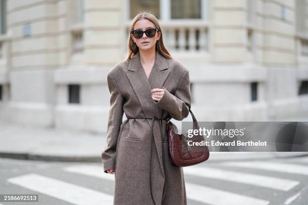 Diane Batoukina wears Chanel sunglasses a brown wool long double breasted coat with a thin belt from Aylin Koenig, a burgundy crocodile pattern Gucci...