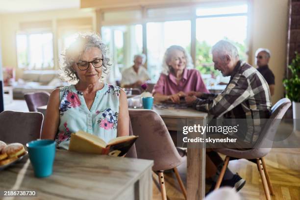 relaxed mature woman reading a book in nursing home. - retirement community stock pictures, royalty-free photos & images