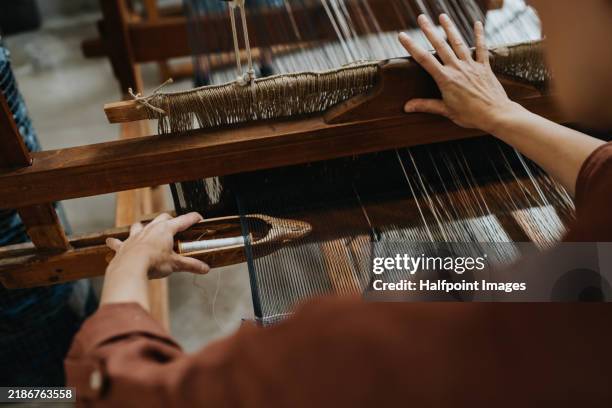 close up of woman’s hand working with threads on wooden loom, weaving handmade product. weaving small business for female business owner. circular economy concept. - webstuhl stock-fotos und bilder