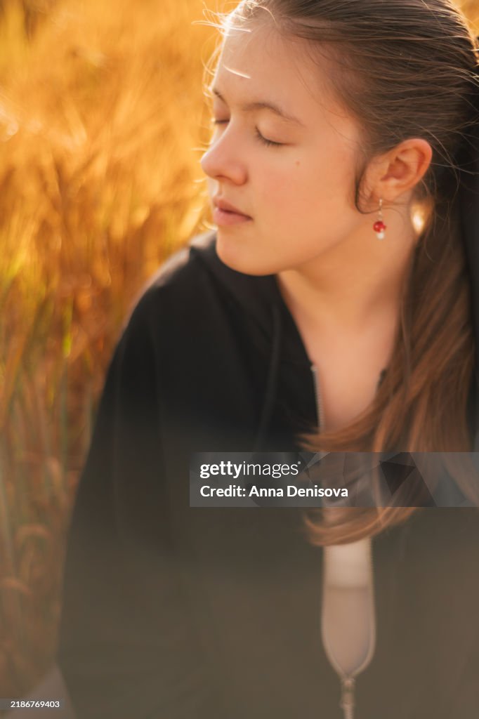Young girl in golden wheat field during sunset