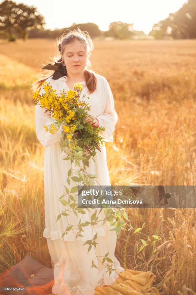 Young girl in golden wheat field during sunset