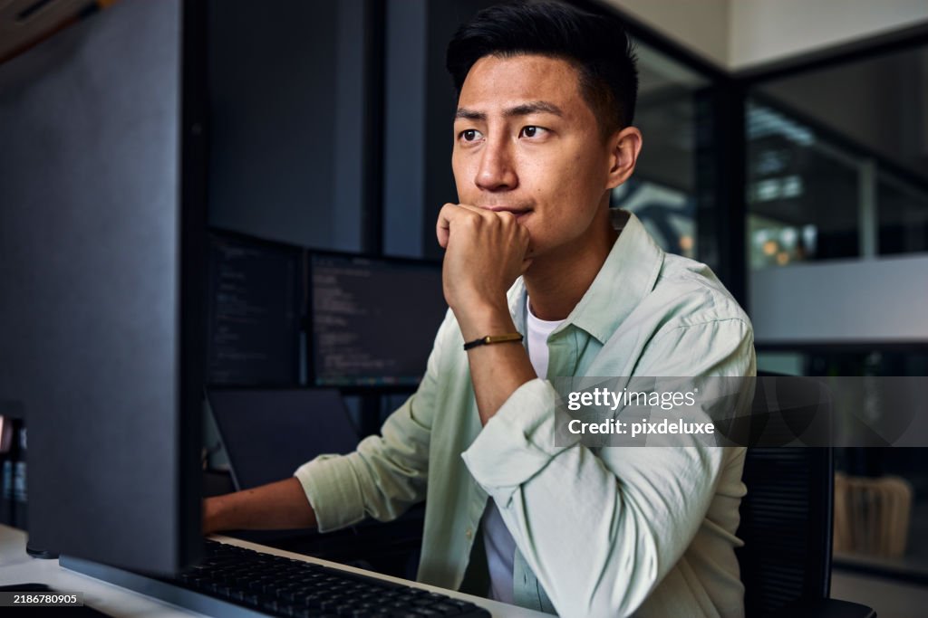 Young asian man working as software developer, coding on computer in modern office