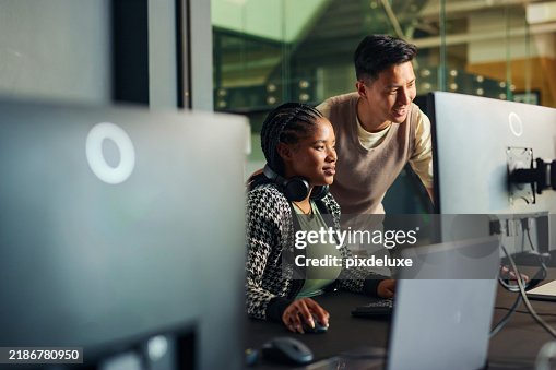 Software engineers collaborating on a project, analyzing code on computer monitors in office Software engineers collaborating on a project, analyzing code on computer monitors in office