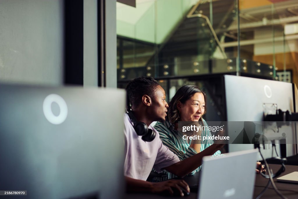 Programmers working together on a computer in office discussing a project