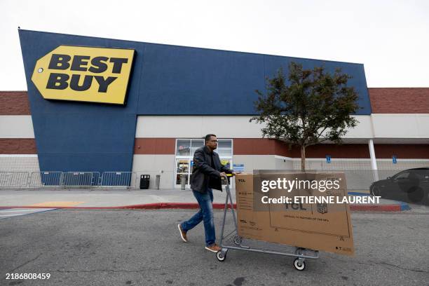 Man pushes a cart with a television in front of a Best Buy store on Black Friday in Montebello, California, November 29, 2024. The annual Black...