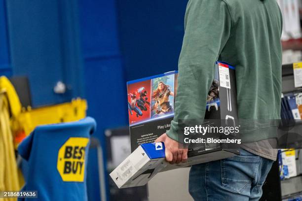 Shopper carries a Sony PlayStation 5 and controller inside a Best Buy store on Black Friday in Pinole, California, US, on Friday, Nov. 29, 2024....