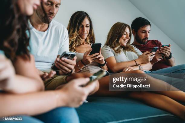 a group of friends are using smart phones at home on the sofa - fake news stock-fotos und bilder