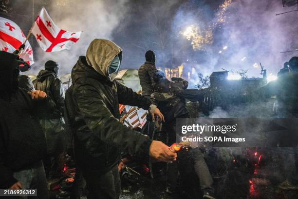 Pro-European protester prepares to throw a firework at police from behind a makeshift barricade during an anti-government protest. Following a...