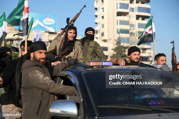 Anti-government fighters brandish their guns as they ride a vehicle in Syria's northern city of Aleppo on November 30, 2024. Jihadists and their...