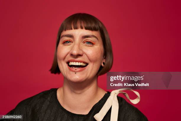 portrait of woman laughing against red background - human joint stock pictures, royalty-free photos & images