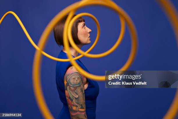 woman with tattooed arm seen through spiral cables - rebellion stock pictures, royalty-free photos & images