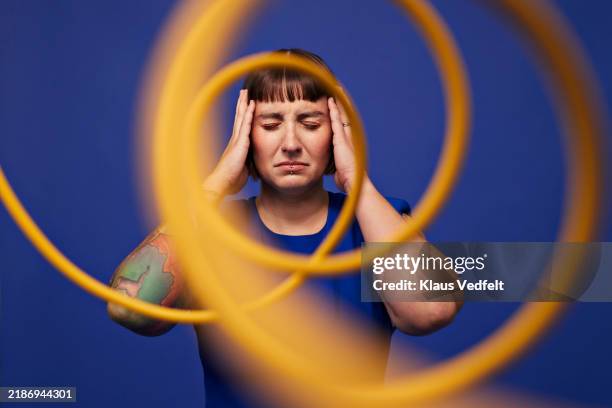woman with head in hands behind spiral cables - mal de tête photos et images de collection