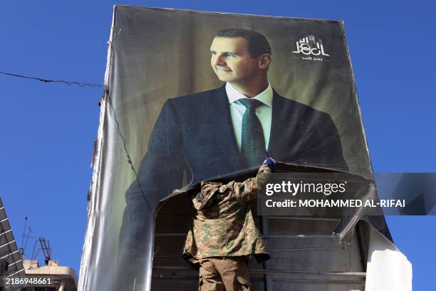 An anti-government fighter tears down a portrait of Syria's President Bashar al-Assad in Aleppo, after jihadists and their allies entered the...