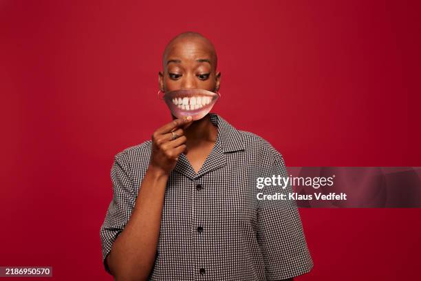 non-binary person holding teeth cut out - fake-sick-day stock pictures, royalty-free photos & images