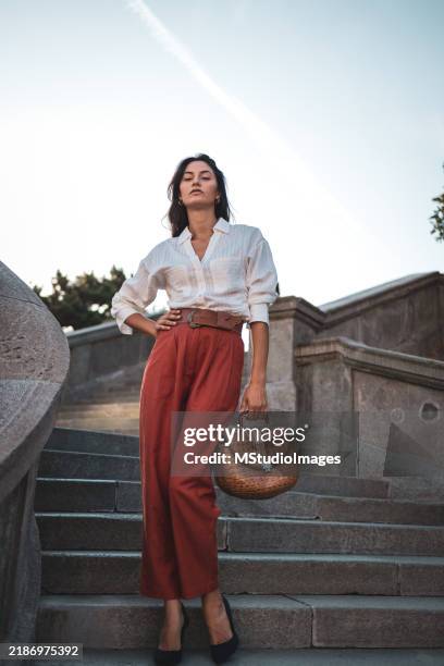 confident woman standing on outdoor steps with handbag - aparência imagens e fotografias de stock