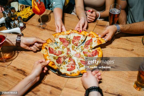 six young people taking a slice of pizza in a pub - pizza imagens e fotografias de stock