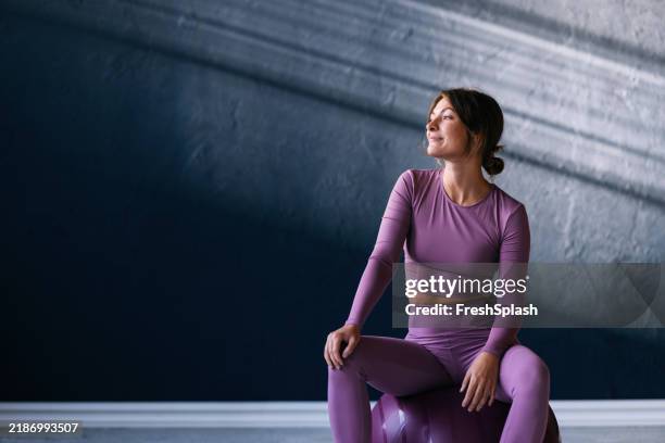 young woman in athletic wear sitting on fitness ball - female likeness stock pictures, royalty-free photos & images