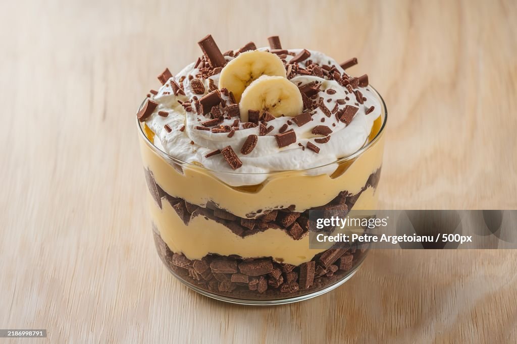 A trifle dessert with layers of banana,Chocolate biscuit,And cream cheese