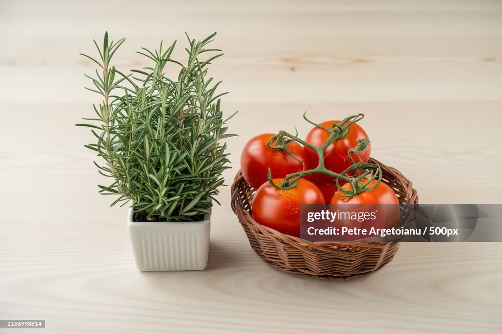 Fresh rosemary and tomatoes isolated on a light wooden background