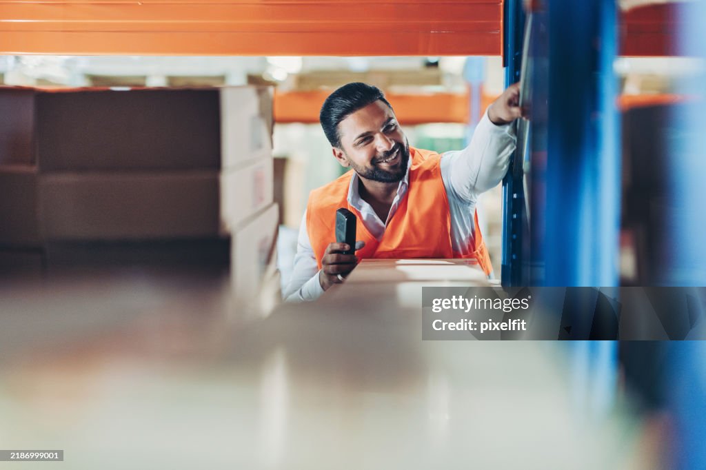 Warehouse worker with bar code reader moving packages