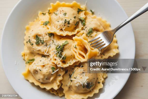 a plate of pasta,cappelletti in butter sauce,garnished with herbs and a sprinkle of cheese - tortellini foto e immagini stock