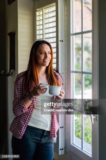 femme au foyer textos sur téléphone intelligent - volet à lames photos et images de collection