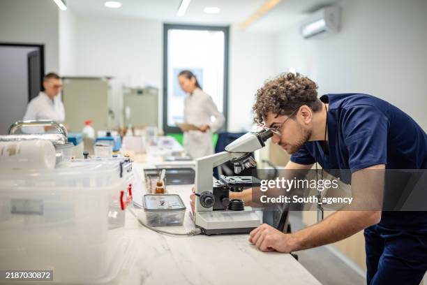 lab technician diligently examining through microscope - life sciences research stock pictures, royalty-free photos & images