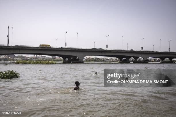 Men swim near the third mainland bridge in Lagos, on November 30, 2024.