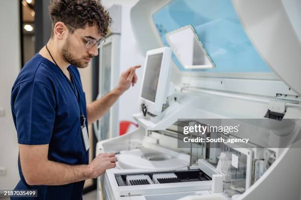 lab technician using advanced medical equipment carefully - medische apparatuur stockfoto's en -beelden