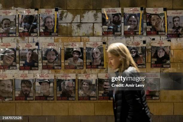 Woman walks by a wall covered with photos of hostages held in Gaza Strip on November 30, 2024 in Tel Aviv, Israel. After the Lebanon cease-fire, the...