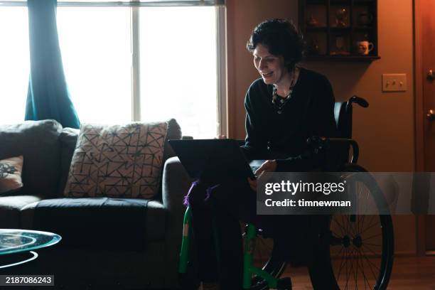 woman with multiple sclerosis uses digital tablet at home - multiple sclerose stockfoto's en -beelden