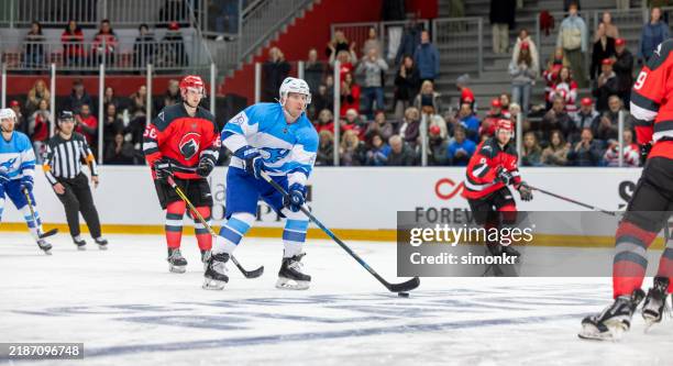 der blaue spieler kontrolliert den puck, während die gegner näher kommen - verteidiger eishockey stock-fotos und bilder