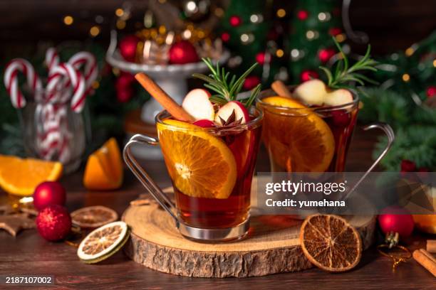 weihnachtslicher rotwein mit dekoration, orange, zimt und tannenbaum auf holztisch - heißes getränk stock-fotos und bilder