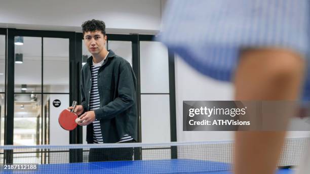 hispanic latin young man playing table tennis in an office setting - table tennis stock pictures, royalty-free photos & images